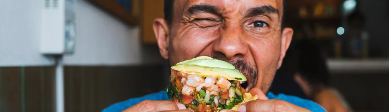 Homme mangeant un tacos aux crevettes